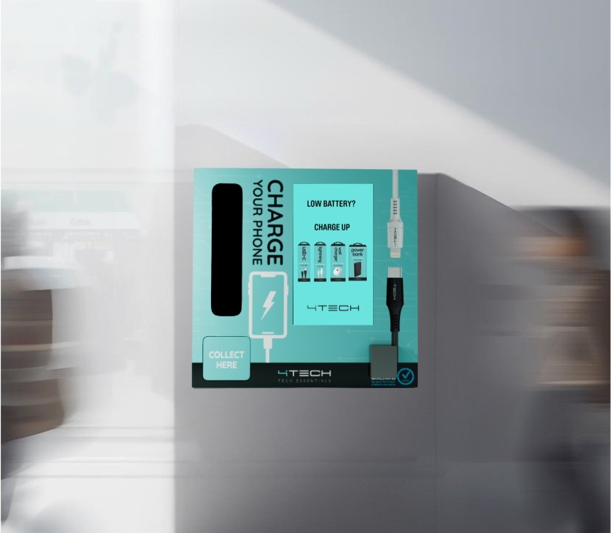A wall-mounted teal 4Tech Charge Your Phone machine in a bright transit space, stocked with USB-C and lightning cables, chargers and power banks, with a Collect Here pickup hatch
