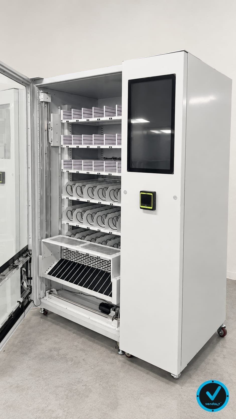 WanderVend pilot machine with push rod trays for boxed products above spiral coils, showing the elevator delivery cradle